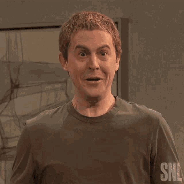 a man in a gray shirt is doing a snl dance