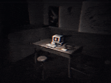 a computer on a desk in a dark room with a drawing on the wall that says " i love you "