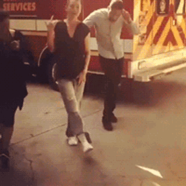 a man and a woman are dancing in front of a fire truck that says services on it