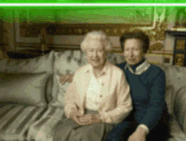 two elderly women are sitting on a couch and posing for a photo