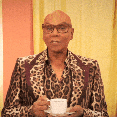 a man in a leopard print jacket is holding a cup of tea