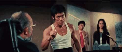 a man in a white tank top is standing in front of two men and a woman in a room .