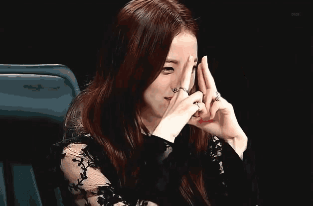 a woman covering her face with her hands while wearing a ring