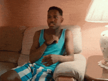 a man in a blue tank top and blue and white striped shorts is sitting in a chair
