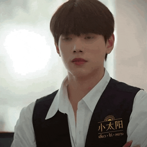 a man wearing a white shirt and a black vest with a sun on it