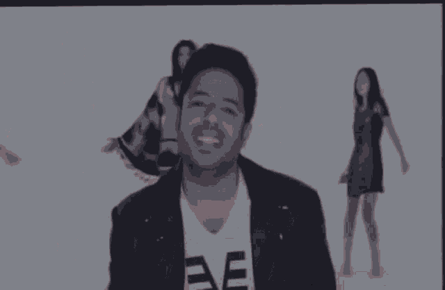 a man wearing a t-shirt that says " ae " stands in front of two women