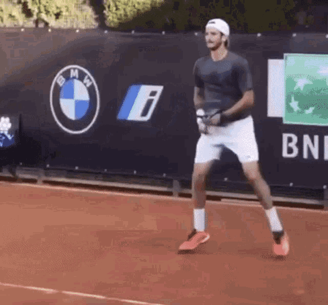 a man is playing tennis in front of a bmw and bnl banner