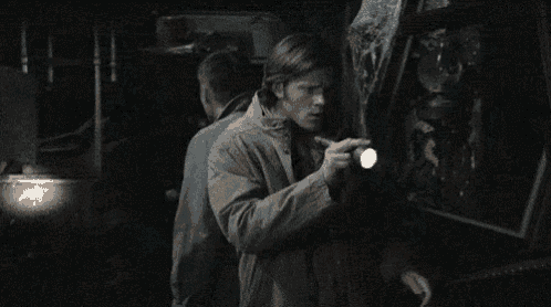 two men are standing next to each other in a dark room .