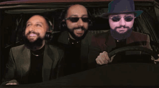 a man with a hat and sunglasses is driving a car with two other men