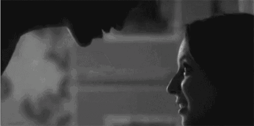 a black and white photo of a man and a woman looking at each other .