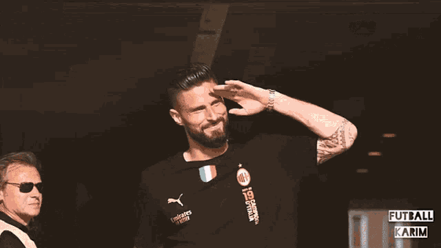 a man with a beard wearing a black shirt that says ac milan on it