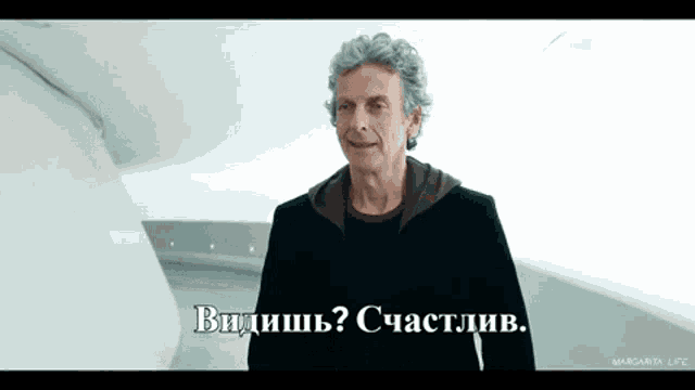 a man with gray hair is smiling and says " видишь "