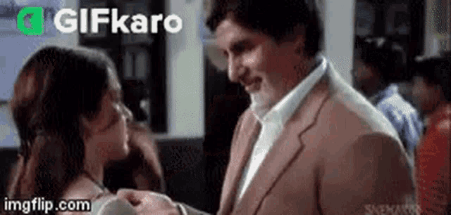 a man in a suit and a woman in a dress are kissing each other .
