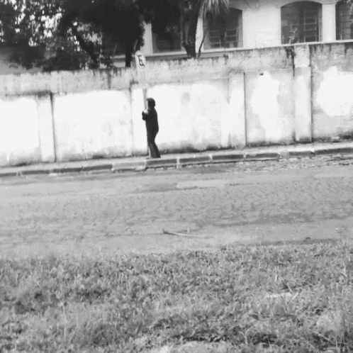 a black and white photo of a person walking down a sidewalk with a sign that says 5