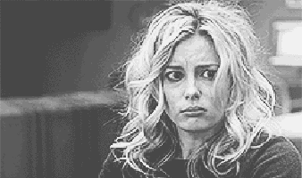 a black and white photo of a woman with long blonde hair making a funny face .