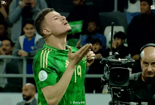 a soccer player in a green jersey with the number 19 on it