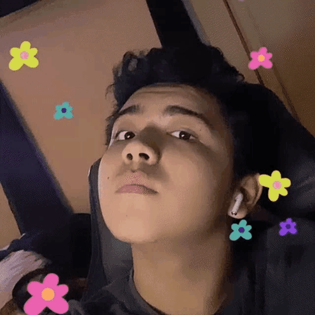 a young man is sitting in a chair with flowers coming out of his ears .