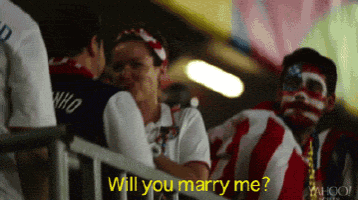 a woman asks a man if he will marry her in a stadium