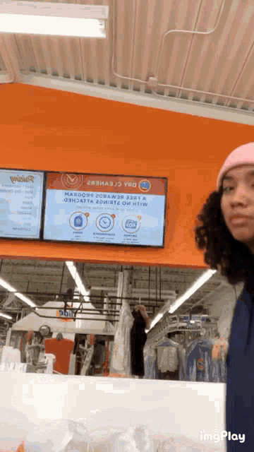 a woman in a pink hat is standing in front of a sign that says ' marcon ' on it