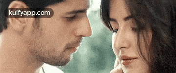a man and a woman are looking into each other 's eyes and touching their noses .