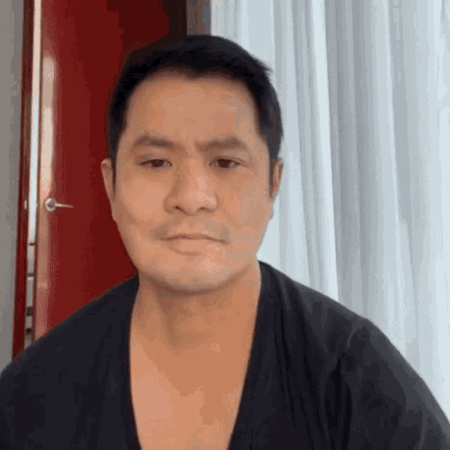 a man is wearing a black shirt and looking at the camera