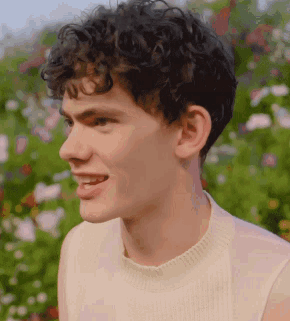 a young man with curly hair wearing a white sweater