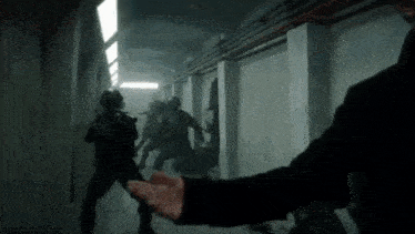 a man is reaching out towards a group of soldiers in a tunnel .