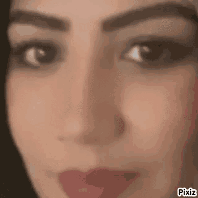 a close up of a woman 's face with a blurred background and red lips .