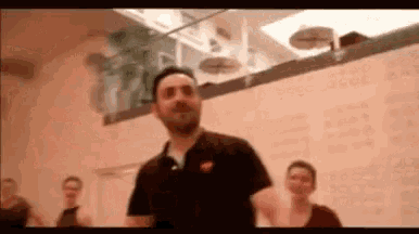 a man is dancing in front of a group of people in a room .
