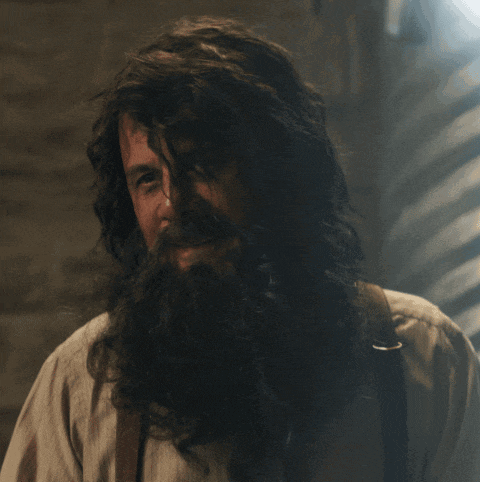 a man with long hair and a beard is looking down