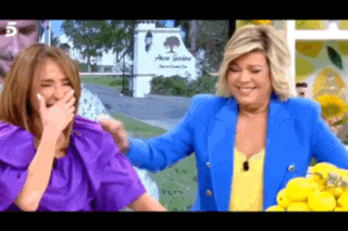 a woman in a blue jacket is laughing with another woman in a purple dress .