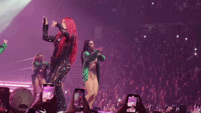 a woman with red hair and a green jacket is dancing on stage