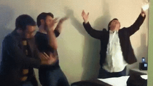 a group of men are dancing in a room with their arms in the air