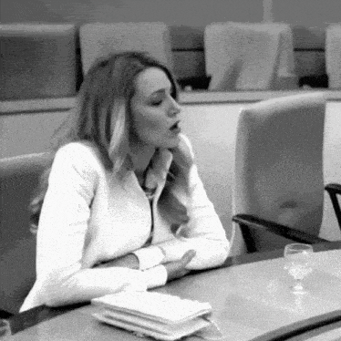 a woman in a white jacket sits at a table