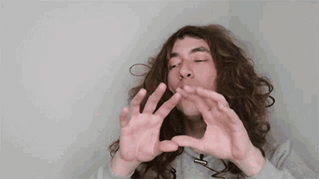 a man with curly hair is making a funny face with his hands in front of the word iumildi .