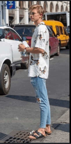 a man wearing a shirt with horses on it is standing on a street