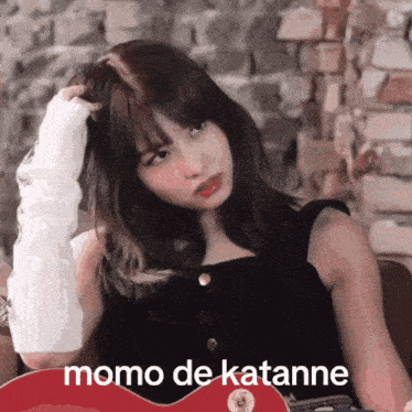 a woman holding a red guitar with momo de katane written on the bottom
