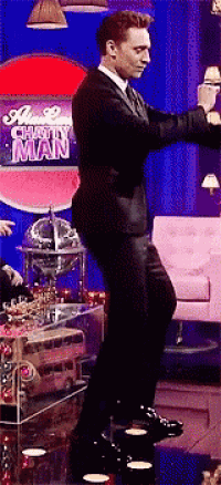 a man in a suit is dancing on a stage in front of a sign that says happy man .