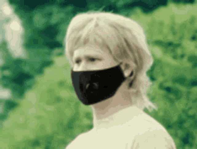 a man wearing a black face mask and a wig .