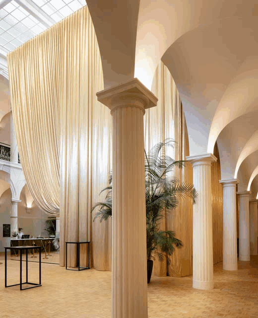 a large room with columns and curtains on the wall