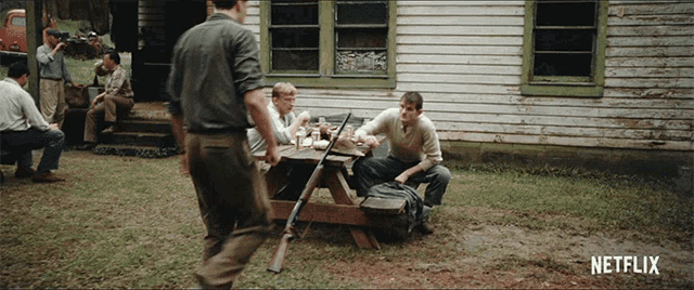 a group of men are sitting at a picnic table with a netflix logo in the corner
