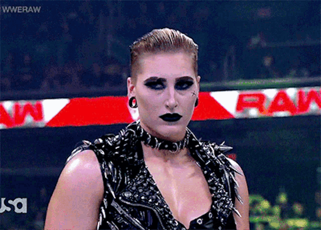 a woman stands in front of a wwe raw banner