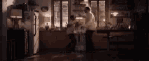 a man and a woman are dancing in a kitchen .