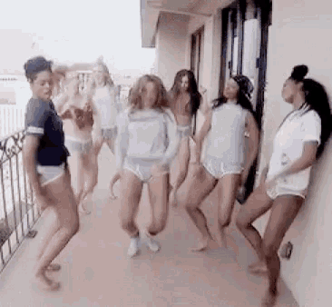 a group of women are dancing on a balcony while standing next to each other .