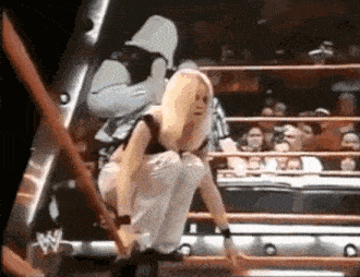 a woman is kneeling down in a wrestling ring with a referee behind her .