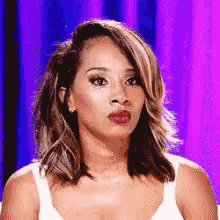 a woman in a white tank top is making a face .