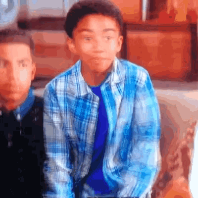 a young boy wearing a blue plaid shirt looks at the camera