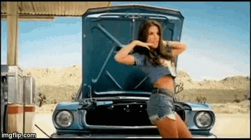 a woman is standing next to a blue car with the hood open .