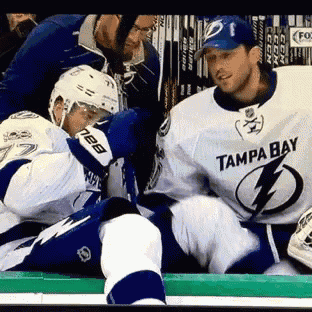 a hockey player wearing a tampa bay jersey sits on the bench