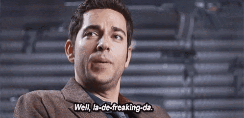 a man in a suit and tie is talking to someone and saying `` well , la-de-freaking-da . ''